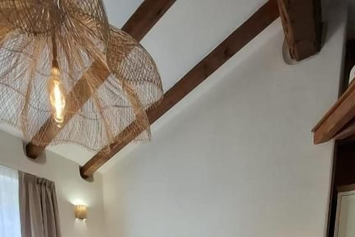 A bedroom with a bed, bedside tables, a chair, and a hanging light fixture.