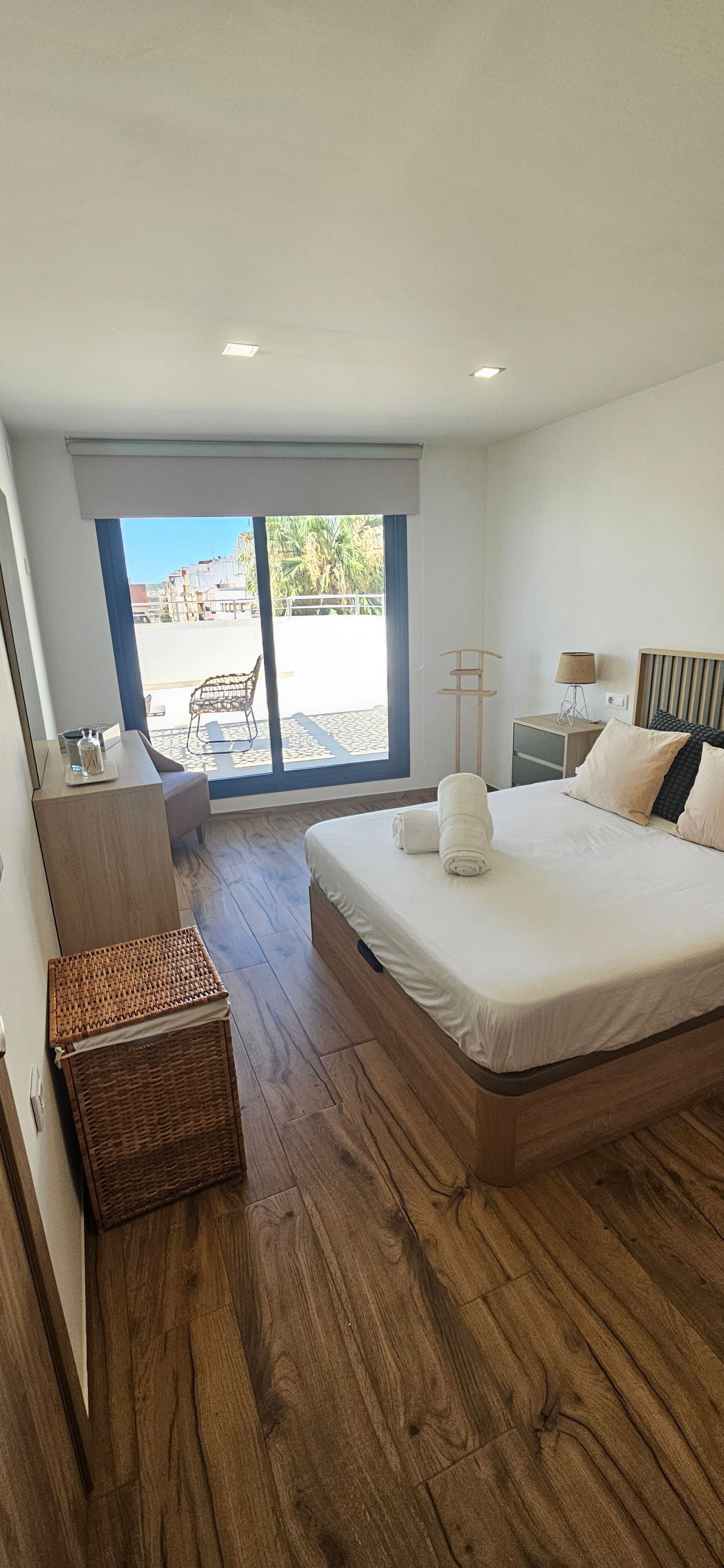 Un dormitorio con una cama grande, un escritorio, una silla y vistas al exterior.