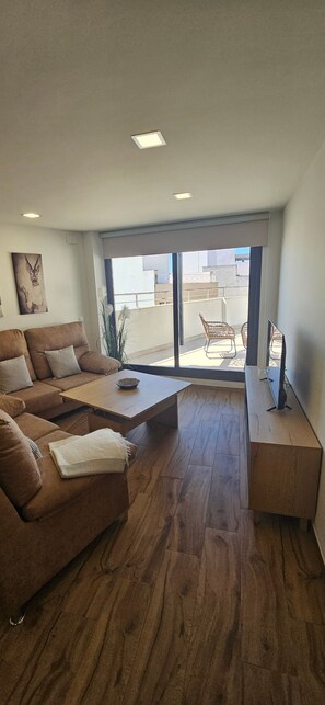 Ein modernes Wohnzimmer mit einer braunen Couch, einem Couchtisch und einer TV-Bank.