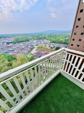 Ein Balkon mit weißer Reling, der auf ein Wohngebiet mit Häusern und Grünflächen blickt.