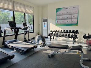 A gym with exercise equipment, including a treadmill, elliptical, and dumbbells. - Royal Oceancrest Panglao 1 (Dauis)