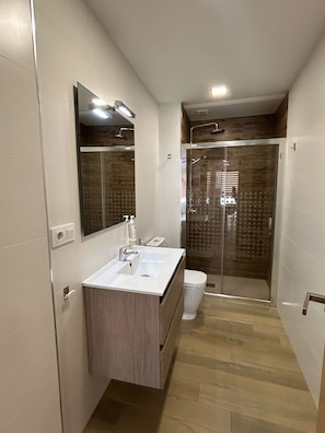 A modern bathroom with a sink, mirror, and shower. - Central penthouse apartment with large terrace (Puente Genil)