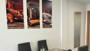 Ein Essbereich mit einem Holztisch, vier Stühlen und drei gerahmten Bildern an der Wand.