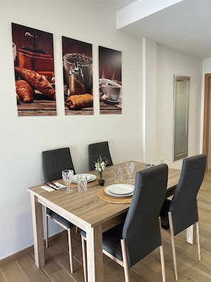 A dining area with a wooden table, four chairs, and three framed pictures on the wall. - Central penthouse apartment with large terrace (Puente Genil)