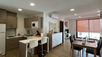 Una cocina moderna con comedor, suelo de madera y luces empotradas en el techo.