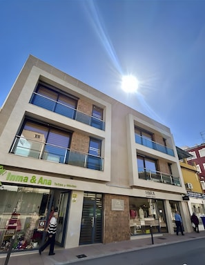 A multi-story building with storefronts on the ground floor, including a visible clothing store named 'Inma & Ana.' - Central penthouse apartment with large terrace (Puente Genil)