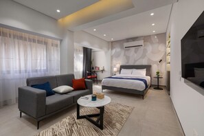 Ein modernes Hotelzimmer mit einer Schlafcouch, einem Bett, einem kleinen Tisch und einem Fernseher.