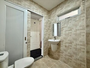 Ein Badezimmer mit Toilette, Waschbecken und einer Tür zu einem weiteren Raum.