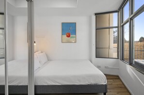 Un dormitorio moderno con una cama grande, un cuadro en la pared y vistas a través de la ventana.