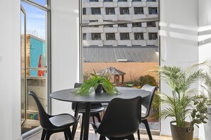 Una habitación moderna con una mesa redonda, sillas negras y una planta en maceta.