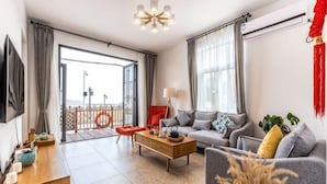 A modern living room with a sofa, coffee table, and a balcony with a railing. - Shatang Jingwan Inn (Xiangshan)