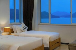 Un dormitorio con dos camas, una mesita de noche, una lámpara y vistas al agua.