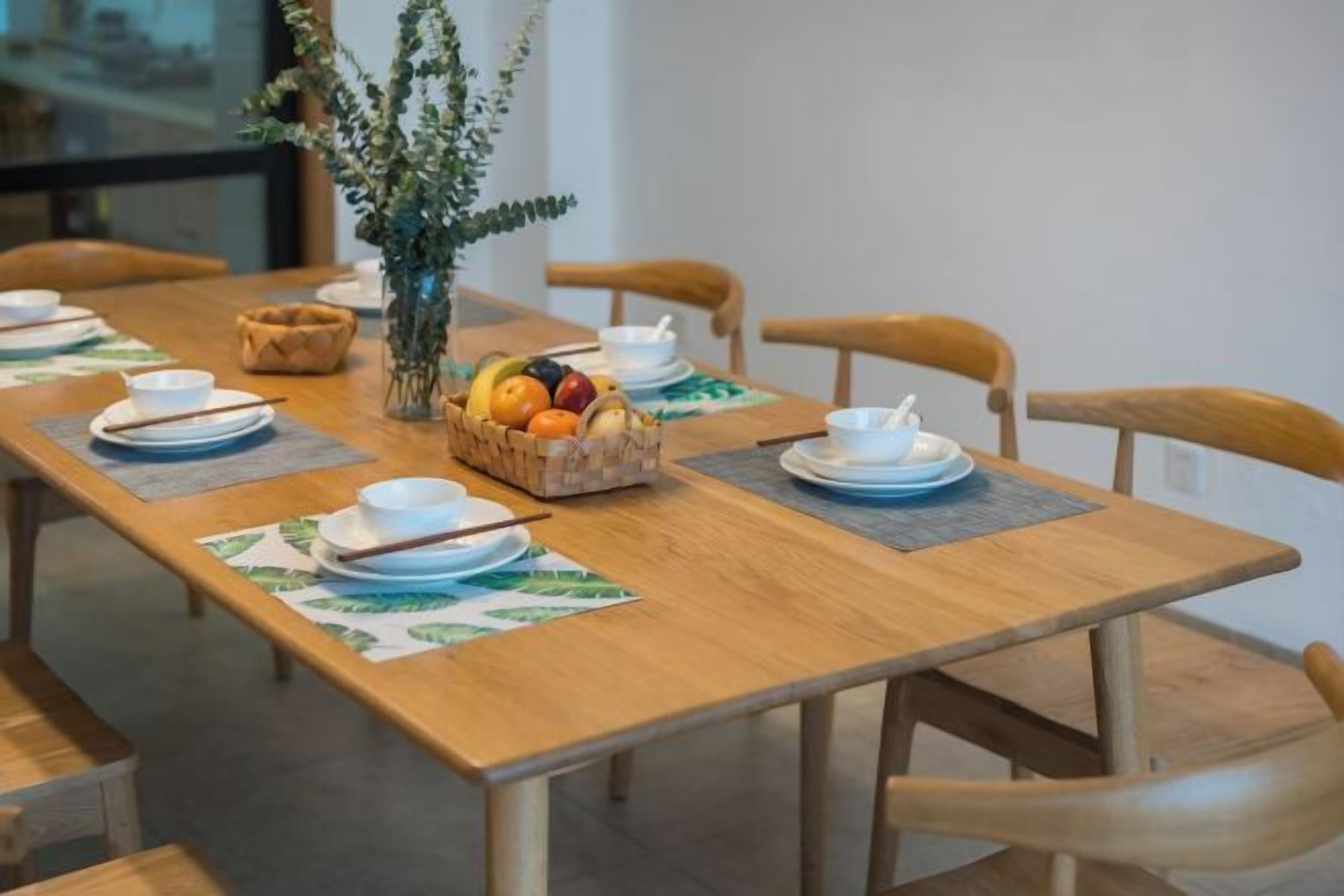 A dining table set with plates, bowls, and a fruit basket.
