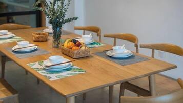 A dining table set with plates, bowls, and a fruit basket.