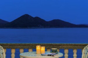 Un balcón con una mesa, dos velas y un libro.