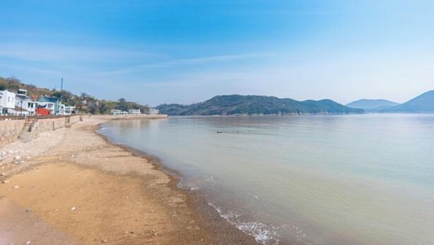 A beach with a clear sky, calm water, and distant hills. - Shatang Jingwan Inn (Xiangshan)