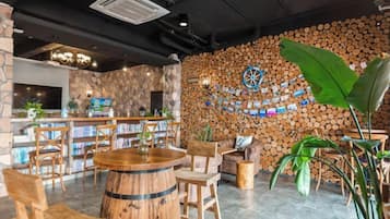 Uma área de bar com móveis de madeira, um alvo de dardos e uma parede de pedra com um relógio.