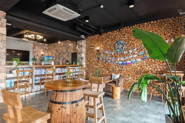 Un espace bar avec des meubles en bois, un jeu de fléchettes et un mur en pierre orné d’une horloge.