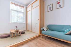 A room with a tatami mat floor, a blue sofa, a wooden table, and a sliding door closet. - Shatang Jingwan Inn (Xiangshan)