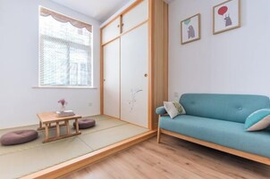 Una habitación con suelo de tatami, un sofá azul, una mesa de madera y un armario con puerta corredera.