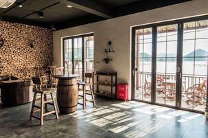 Una habitación amplia con un gran ventanal, un barril de madera y una pared rústica.