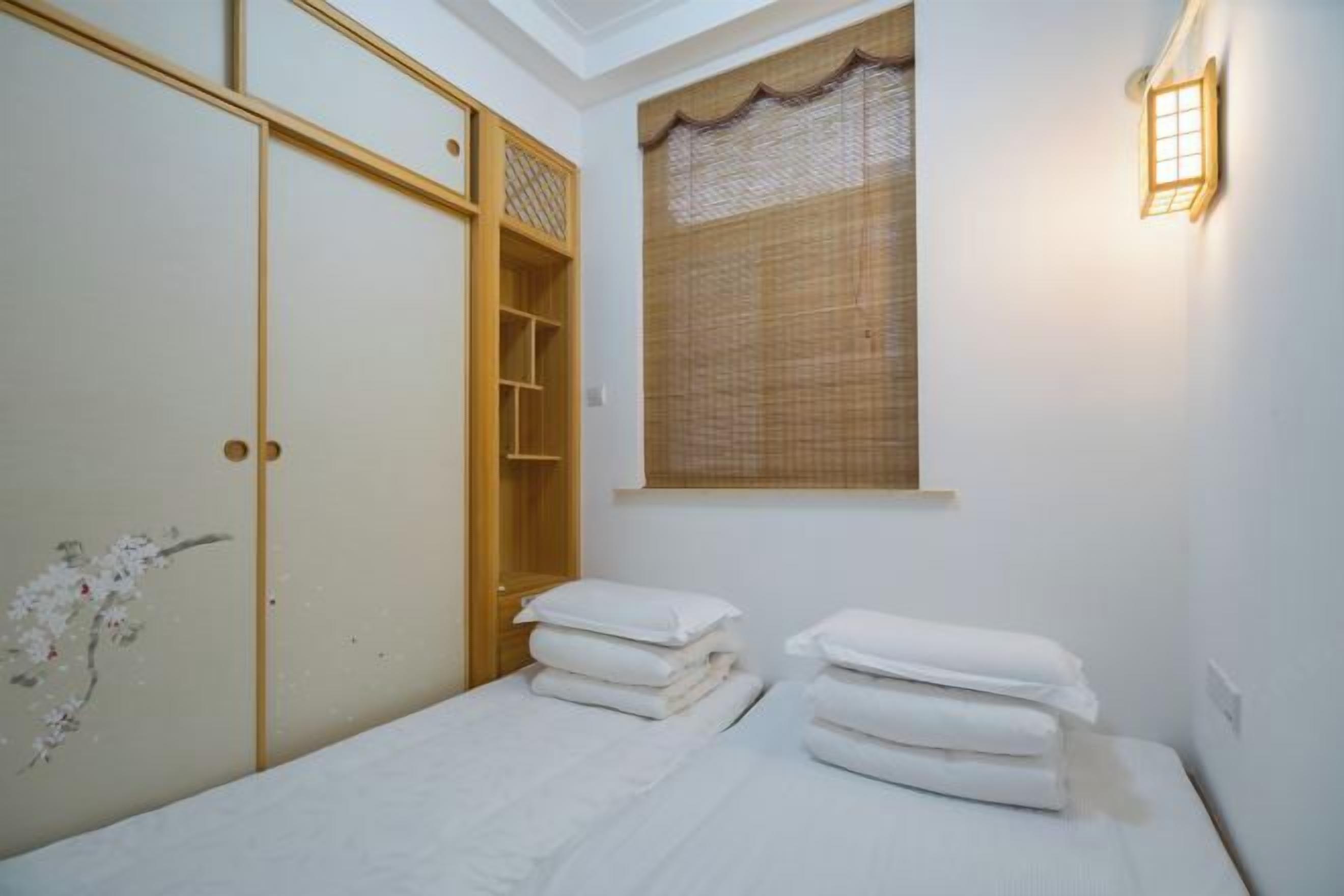 A bedroom with a bed, a wardrobe, and a window with a curtain.