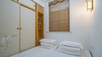 A bedroom with a bed, a wardrobe, and a window with a curtain.