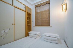 Une chambre à coucher avec un lit, une armoire et une fenêtre avec un rideau.