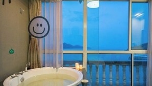 A bathroom with a bathtub, a window with a view, and a smiley face decoration. - Shatang Jingwan Inn (Xiangshan)