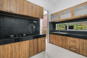 A modern kitchen with wooden cabinets, black countertops, and a built-in microwave.