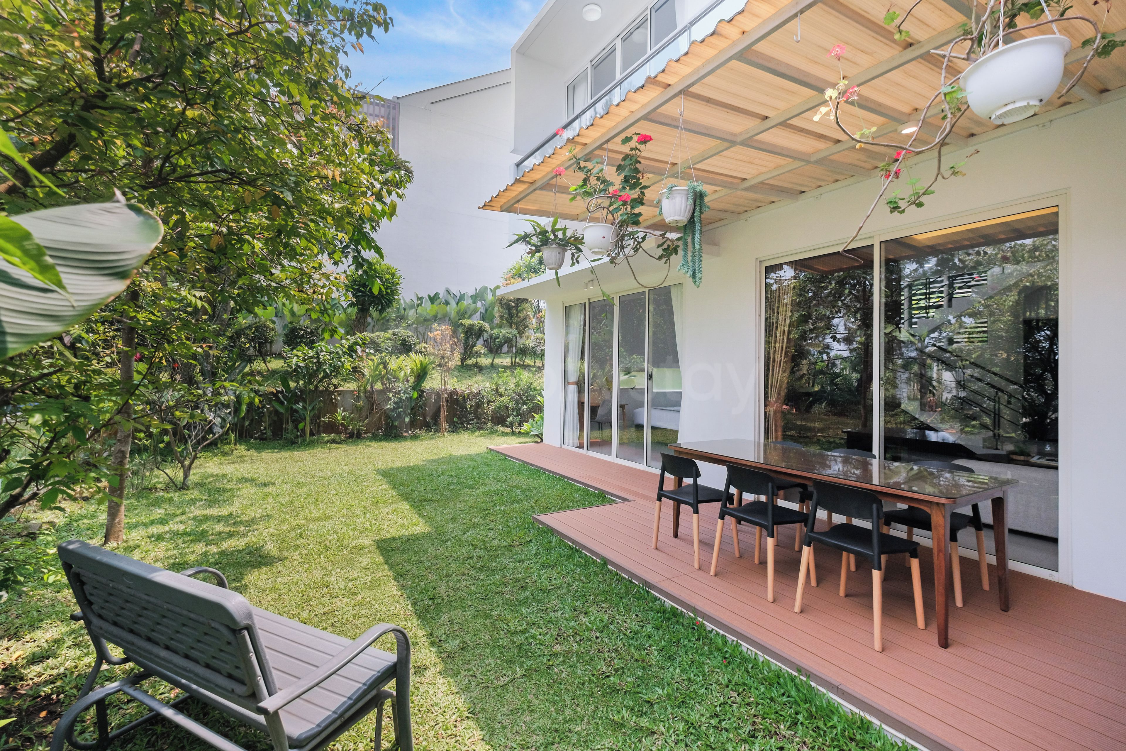 Eine moderne Außenpatio mit Esstisch und Stühlen, umgeben von einem gepflegten Rasen und verschiedenen Pflanzen.
