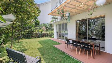 Eine moderne Außenpatio mit Esstisch und Stühlen, umgeben von einem gepflegten Rasen und verschiedenen Pflanzen.