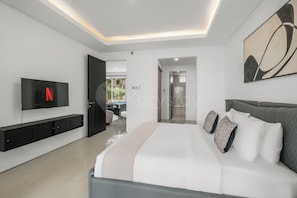 Ein modernes Schlafzimmer mit einem Bett, einem an der Wand befestigten Fernseher und einer Tür zu einem Badezimmer.