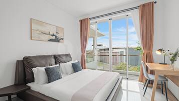 Une chambre moderne avec un grand lit, un bureau et une vue sur l’extérieur.