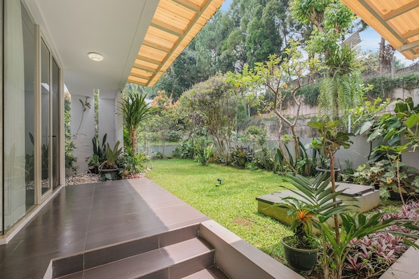 A modern house with a covered patio, a well-maintained garden, and a variety of plants.