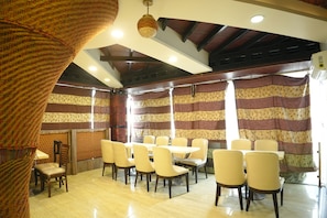 A room with a high ceiling, patterned curtains, and a row of yellow chairs and tables. - Hotel Smriti Star (Bhopal)