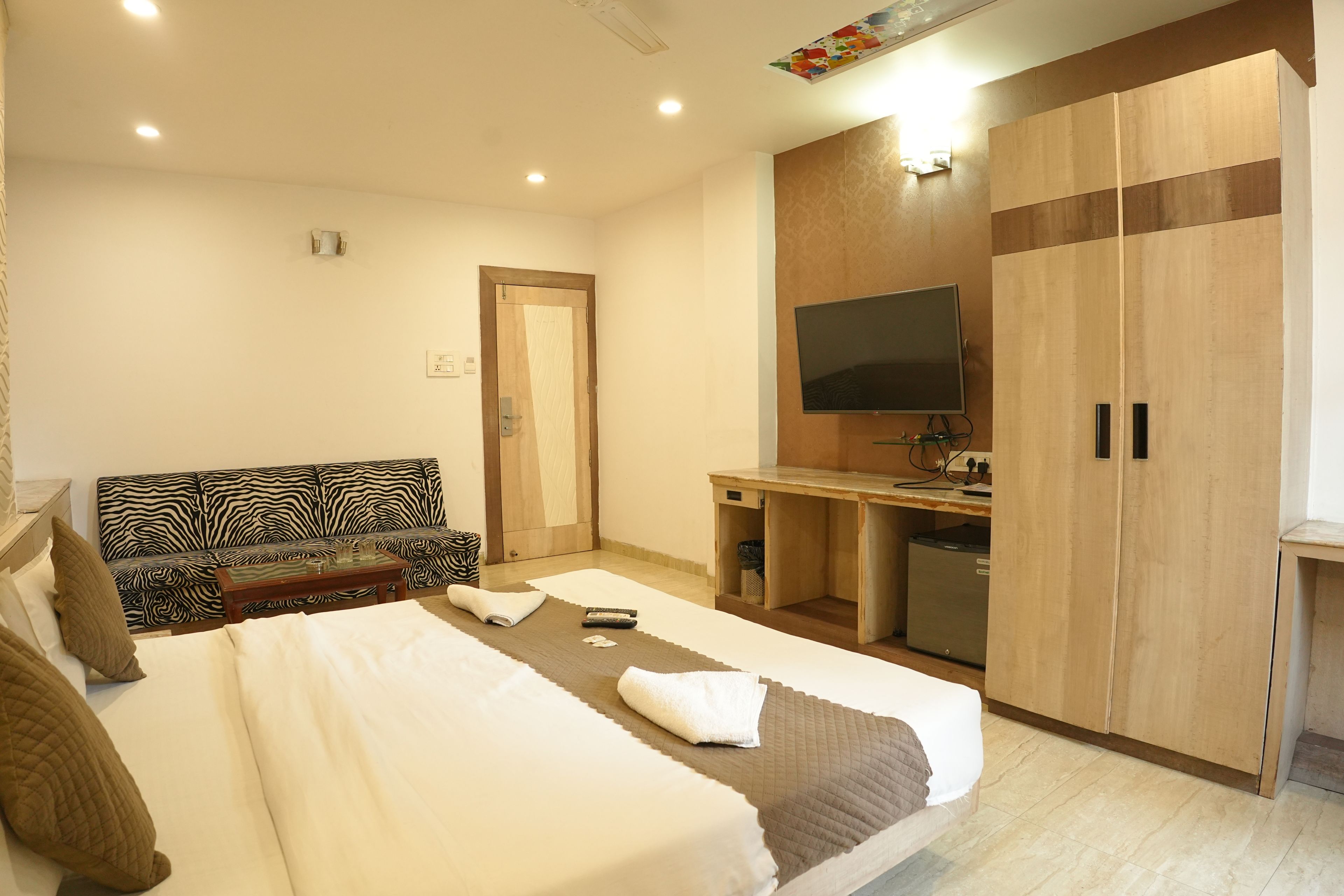 A hotel room with a bed, a sofa, a desk, a television, and a wardrobe.