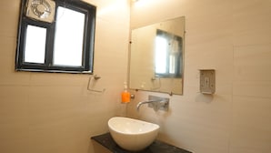 Un baño con un lavabo blanco, un espejo, una ventana y un secador de manos.