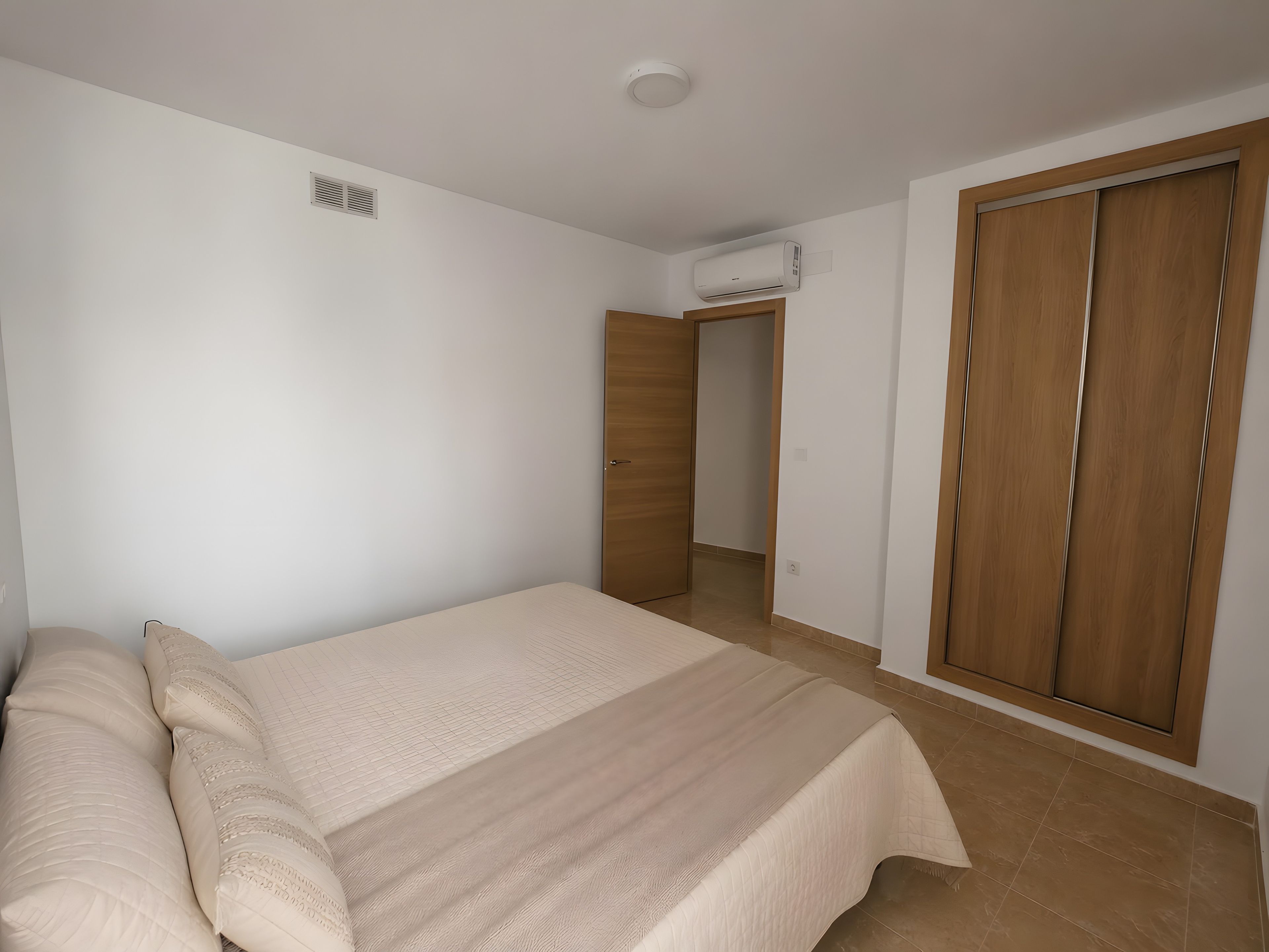 Ein Schlafzimmer mit einem Bett, einem Kleiderschrank und einer Klimaanlage.