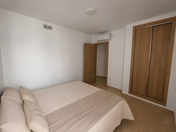 A bedroom with a bed, a wardrobe, and an air conditioning unit.