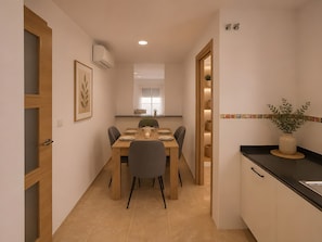 Una cocina moderna con comedor, que incluye una mesa de madera, sillas y una planta en maceta.