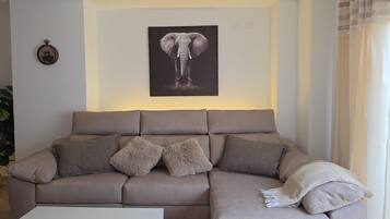 Ein Wohnzimmer mit einer Couch, Kissen, einer Wanduhr und einem gerahmten Bild.