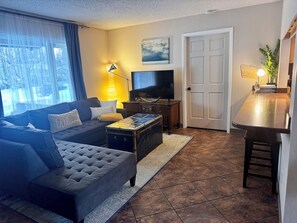 A living room with a sofa, a coffee table, a television, and a cabinet. - Alaska Adventure Basecamp • Sleeps 6 • 
• 3BR / 2Ba • Yard + Fire Pit (Anchorage)