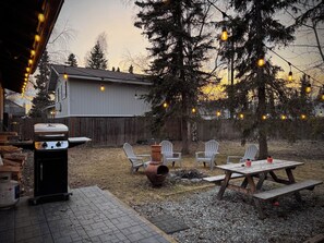 A backyard with a barbecue grill, outdoor seating, and string lights.