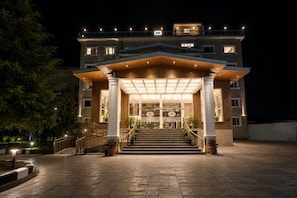 A multi-story hotel with a grand entrance, a staircase leading to the main entrance, and a well-lit facade. - The Platinum Grand Mamta (Srinagar)