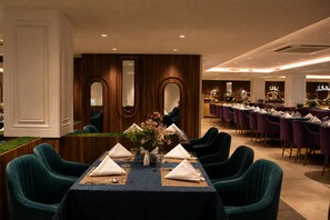 A formal dining area with a long table set for multiple guests, surrounded by upholstered chairs. - The Platinum Grand Mamta (Srinagar)