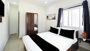 A hotel room with a bed, a wardrobe, a window with curtains, and a wall-mounted TV. - Super Townhouse Badangpet Crossway (Hyderabad)
