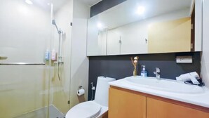 Une salle de bain moderne avec une douche à parois de verre, des toilettes blanches et un meuble-lavabo avec un miroir.