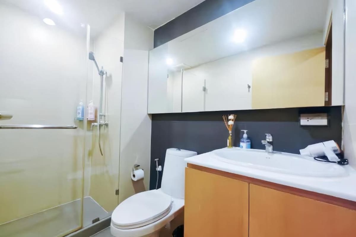 A modern bathroom with a glass shower enclosure, a white toilet, and a vanity with a mirror.