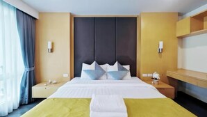 Une chambre d’hôtel comprenant un lit, des tables de chevet, une commode, un bureau et une chaise.